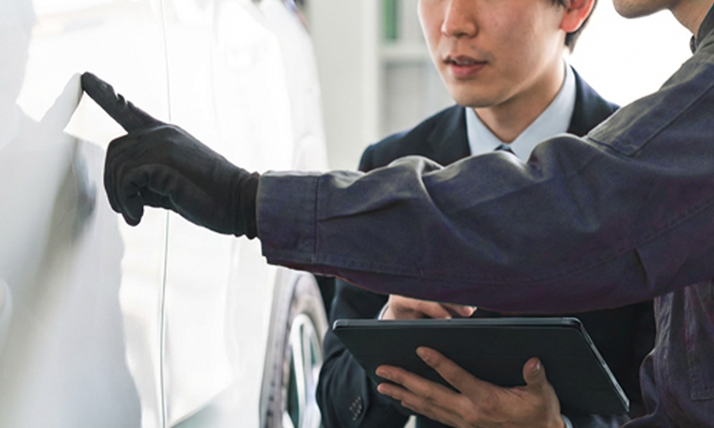 作業員がカーディーラーの担当者に作業内容を説明する様子